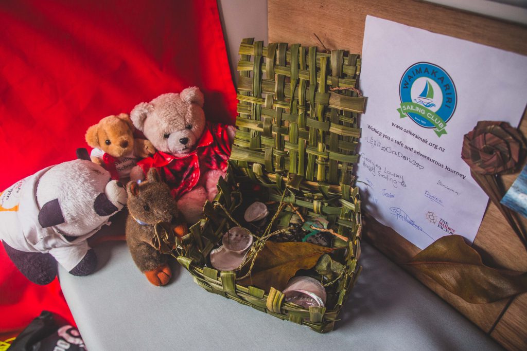 A green flax box holds shells and leaves, with mascots next to it. Mascots are two teddies, a kangaroo and a panda