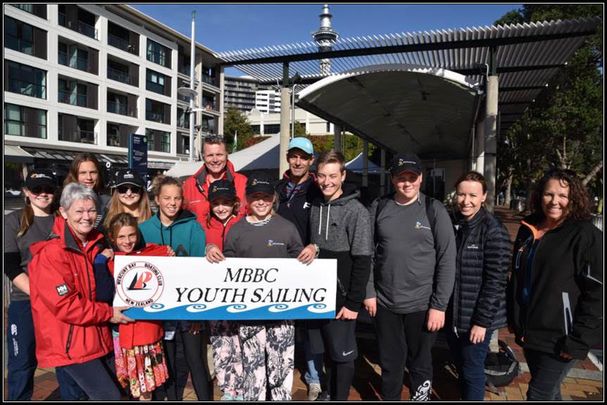 A group from MBBC stand on the Viaduct harbour, holding a MBBC sign