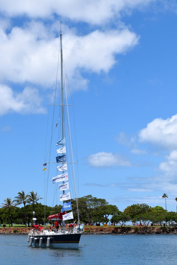 Maiden sails in on a blue calm water with a bright blue sky. Palm trees are behind