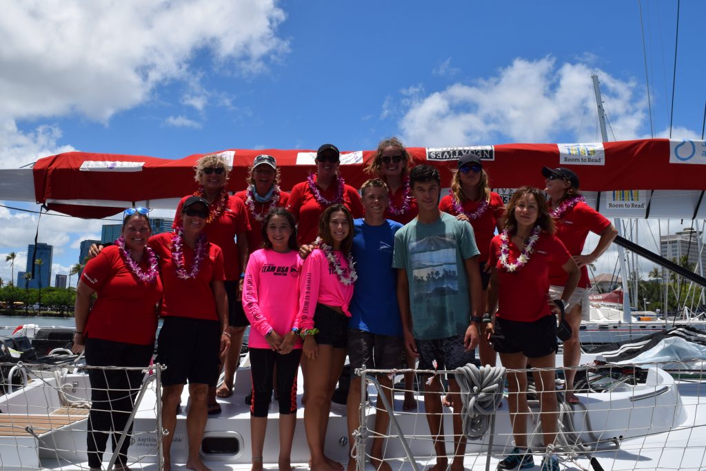 All smiles and leis, with youngsters from the Hawaii yacht club. The Maiden crew stand on deck with a bright blue sky backdrop.
