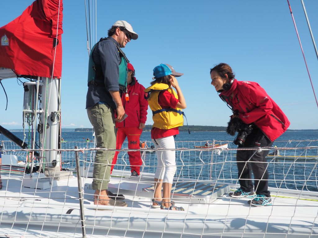 Amalia bends down to speak to a young sailor onboard Maiden 